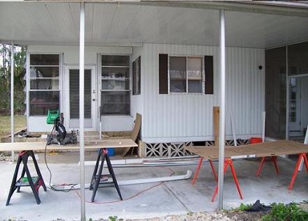 Work in progress on a DIY room enclosure, with sawhorses and tools under an aluminum carport