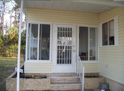 Screen room entry with white aluminum screen door, kickplate and steps